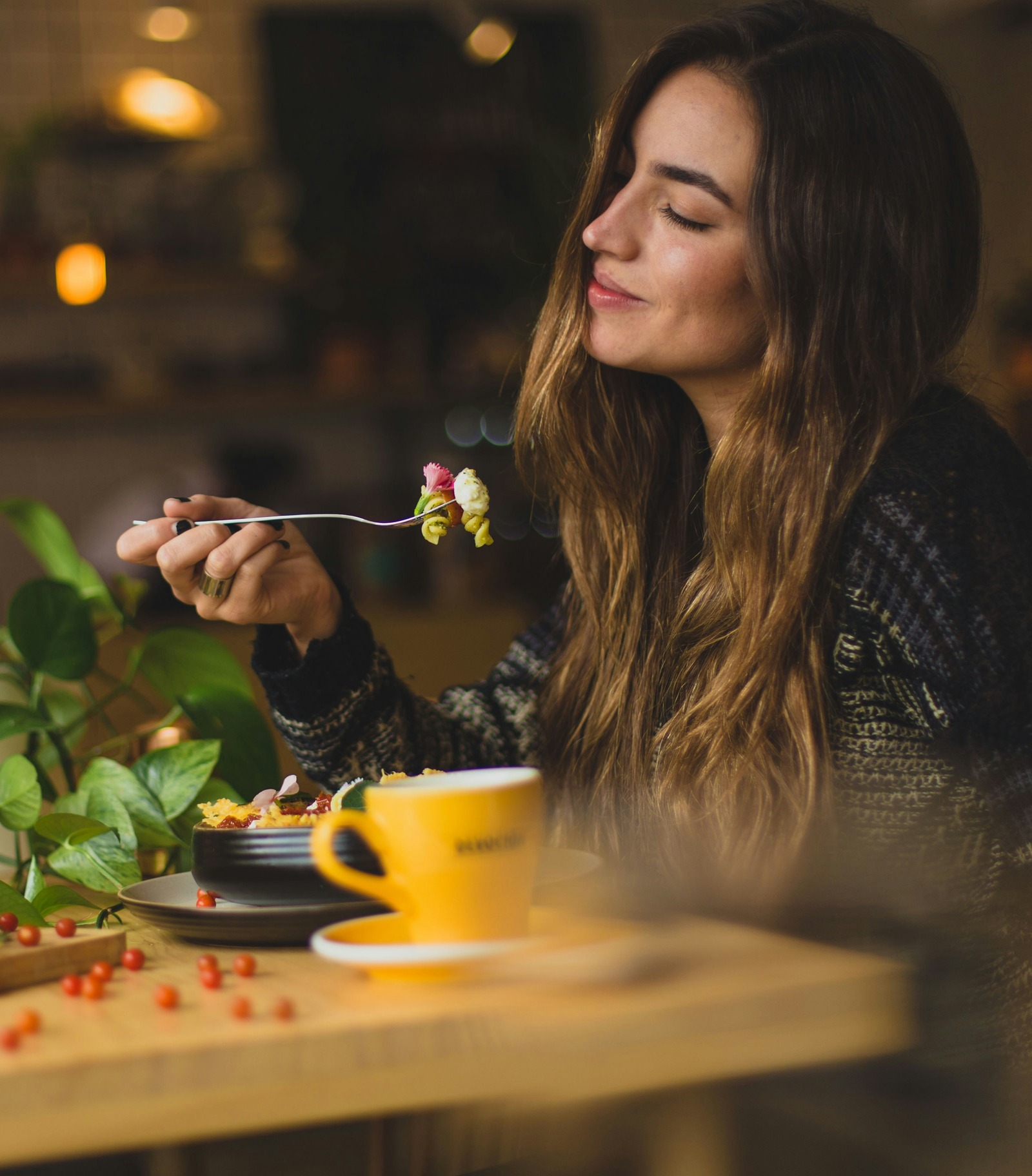 A woman enjoying a meal in warm café lighting.