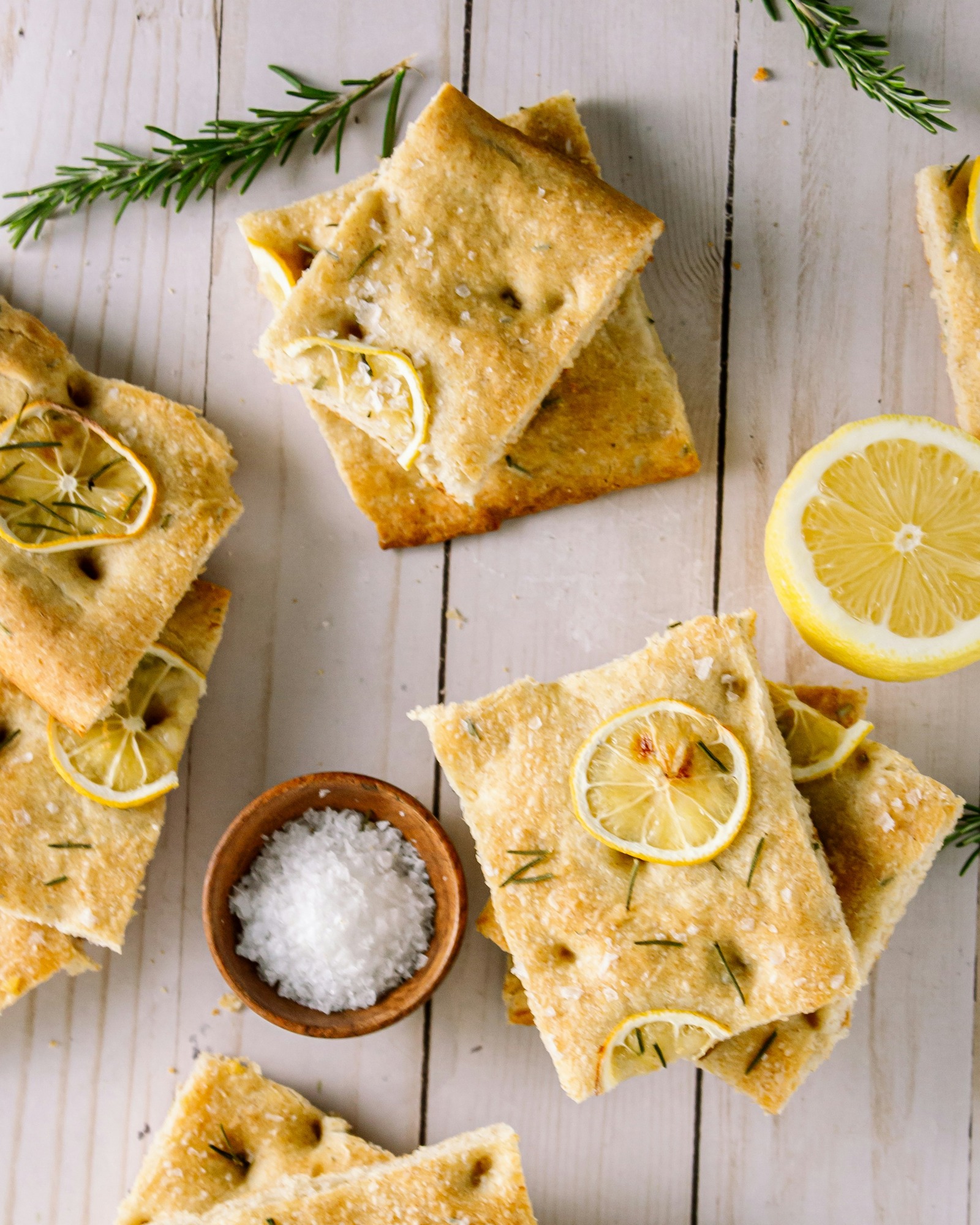 An overhead food photo with lemon rounds and crisps arranged on a light table.